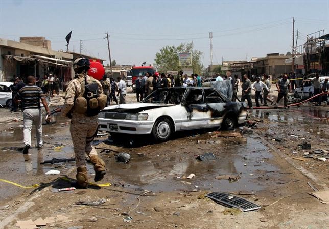  مدنيون وقوات امن عراقية في مكان انفجار سيارة مفخخة بكربلاء امس اب