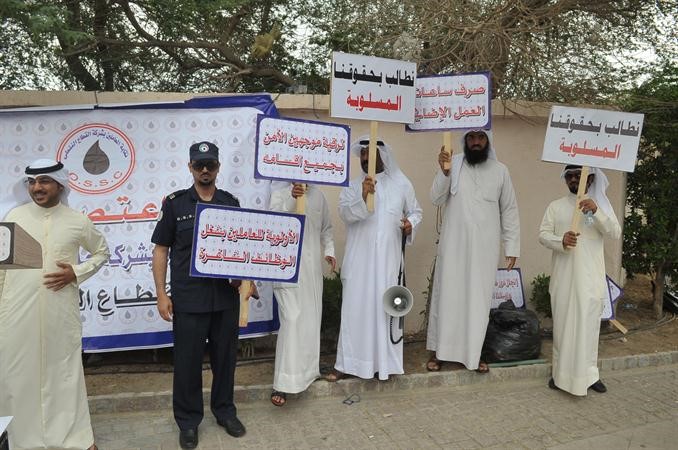 بعض العاملين يرفعون لافتات تبين مطالبهم﻿