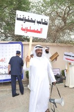 احد العاملين يرفع لافتة للمطالبة بالحقوق﻿