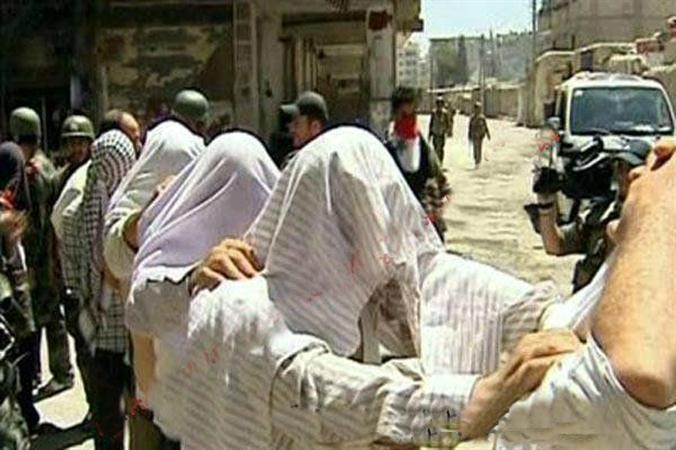 صورة بثها ناشطون تظهر عناصر من الجيش النظامي خلال اقتيادهم عددا من اهالي بلدة البيضا في بانياس الى ساحة البلدة 