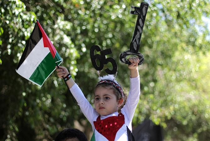 طفلة فلسطينية في غزة ترفع مفتاحا خشبيا للرمز الى حق العودة للديار التي هجروا منها وتحمل رقم 65 للرمز لذكرى النكبة امس افپ