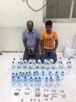 المتهمان وامامهما الخمور المضبوطة