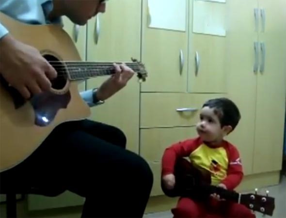 بالفيديو.. طفل عمره عامان يعزف على الجيتار ويغني لفرقة الـ " بيتلز "