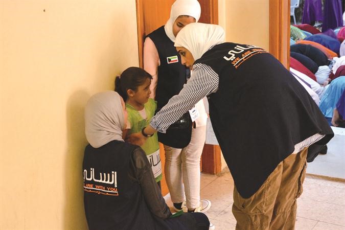 فريق انساني يحاول اقناع طفلة من اللاجئين بالدخول للفصل﻿