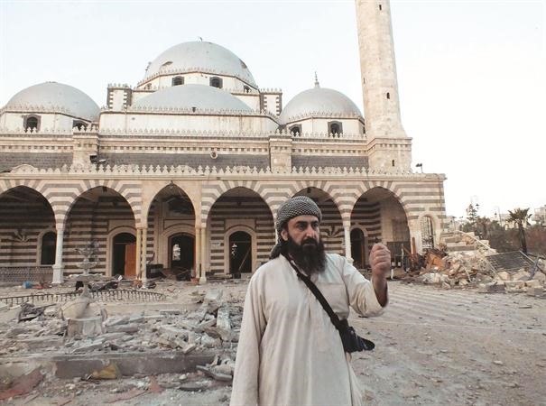 احد عناصر الجيش السوري الحر يقف امام مسجد الصحابي الجليل خالد بن الوليد في حمص وتظهر اثار الدمار بعد قصف النظام له امس الاول رويترز 
