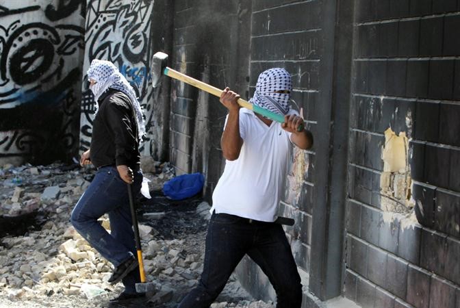  شاب فلسطيني يستخدم معولا لهدم جزء من الجدار الاسرائيلي العازل افب

