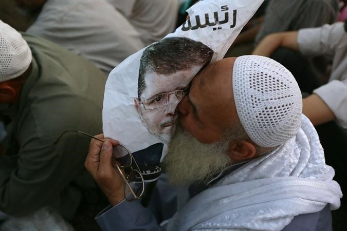 مؤيد للرئيس المعزول محمد مرسي يقبل صورته خلال اعتصام ميدان رابعة العدوية امس الاول افپ