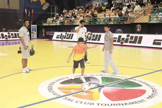طفل يركل الكرة قبل بدء المباريات ويبدو شعار جريدة الانباء احد رعاة البطولة الذهبيين﻿