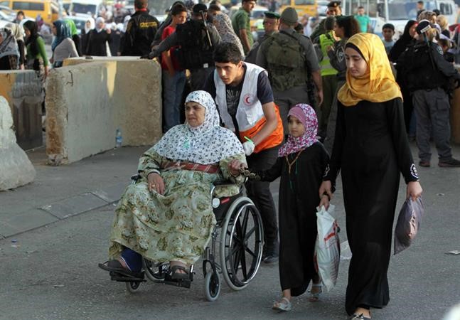 عجوز فلسطينية واسرتها يعبروننقطة تفتيش قلنديا الاسرائيلية في طريقهم للمسجد الاقصى امس 	افپ﻿