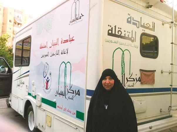 الداعية سلوى الايوب امام احدى سيارات الاسعاف لاغاثة النازحين السوريين