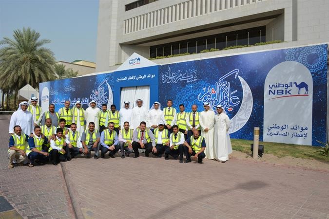 قيادات من البنك الوطني مع فريق المتطوعين امام خيمة الوطني الرمضانية﻿