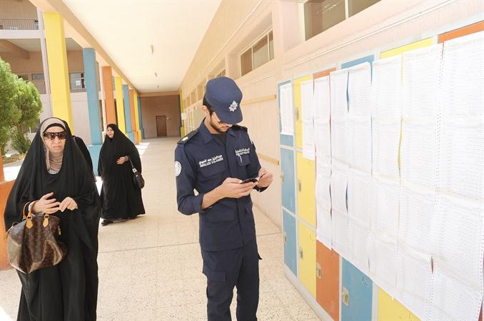 احد رجال الامن يساعد مواطنة في معرفة لجنتها

