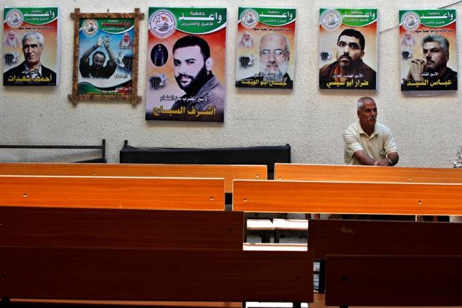 فلسطيني يجلس على مقعد بجانب مقر الصليب الاحمر للمطالبة بالافراج عن المعتقلينا ب 
