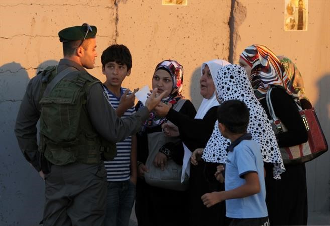 جندي اسرائيلي يفحص هويات فلسطينيين عند معبر قلنديا في طريقهم للمسجد الاقصى امس	 افپ ﻿