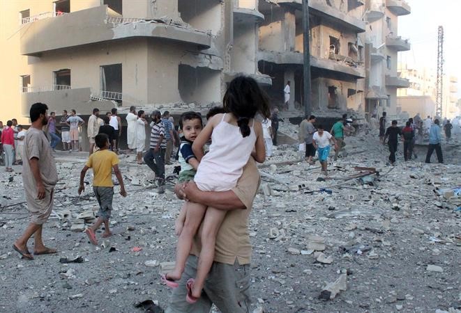 رجل يحمل طفليه بعد ان نجوا من الدمار الذي خلفه استهداف النظام بصاروخ ارض - ارض لمدينة الرقة افپ
