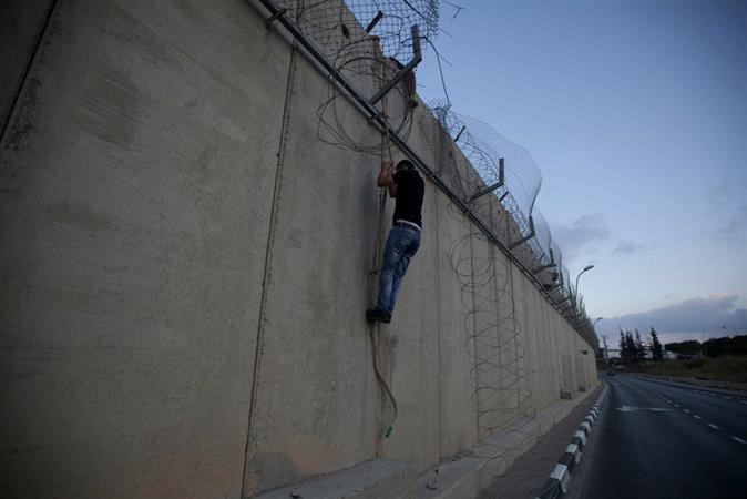 فلسطيني يقفز من فوق الحاجز الاسمنتي الذي يفصل الضفة عن القدس امس الاول 	 ا ف پ ﻿