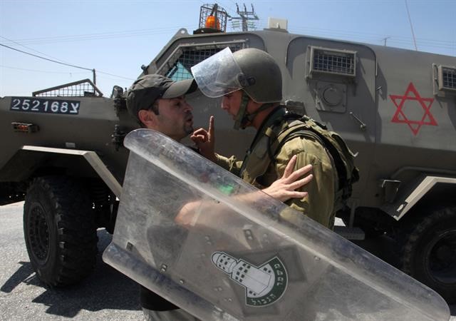  جندي اسرائيلي يعترض متظاهر فلسطيني قرب من احد المستوطات بالضفة الغربية امس 	 افپ ﻿
