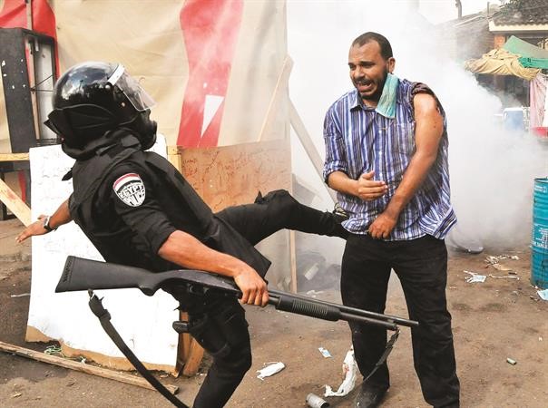 ركلة من احد افراد الامن لاحد مؤيدي الرئيس المصري المعزول محمد مرسي خلال فض اعتصام النهضة الاربعاء الماضي	 اپ﻿