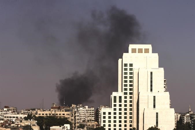 الدخان الاسود يتصاعد نتيجة القصف على حي جوبر في العاصمة دمشق ويبدو فندق الفورسيزنز حيث يقيم مفتشو الامم المتحدة اپ 