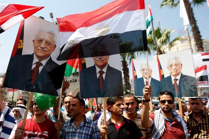  فلسطينيون يرفعون العلمين المصري والفلسطيني وصورا للرئيس عباس في تظاهرة مؤيدة للجيش المصريفي رام الله امس 	اپ ﻿