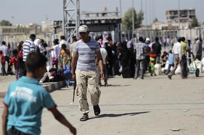 مقاتل من الجيش الحر يؤمن سوريين نازحين الى تركيا عبر معبر باب الهوى رويترز ﻿