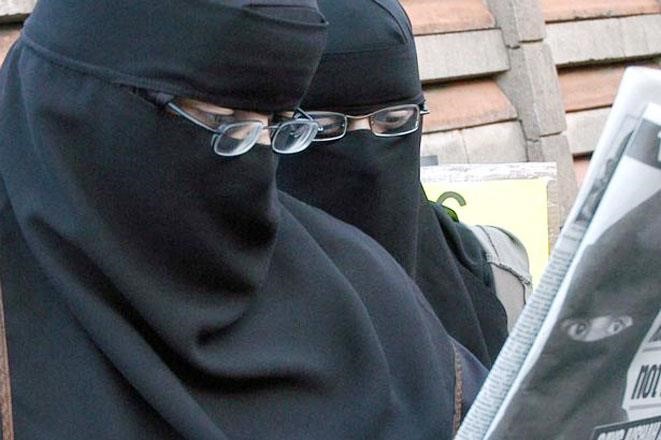 طالبتان منتقبتان تطالعان خبر الحظر في الصحيفة﻿