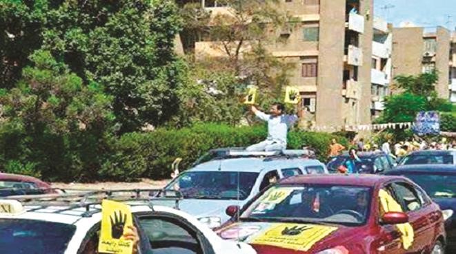 سيد معوض اثناء مشاركته في احدى المظاهرات المؤيدة للرئيس المعزول محمد مرسي حاملا شعار رابعة العدوية﻿