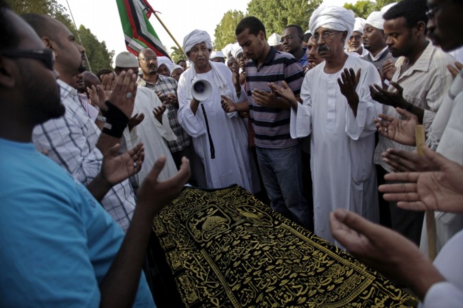  متظاهرون سودانيون يقراون الفاتحة قبيل تشييع جثمان احد المحتجين الذي قضى امس الاول	اپ﻿