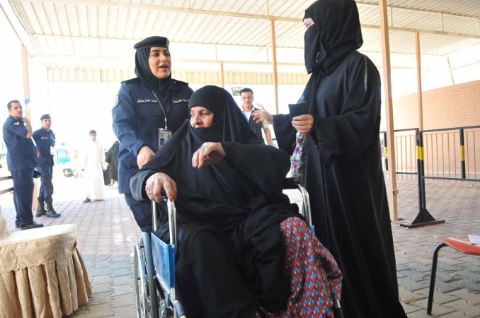 احدى عناصر الشرطة النسائية تساعد مواطنة في الوصول الى اللجنة