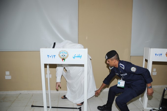 احدافراد الامن يساعد احد كبار السن خلال عملية التصويت
