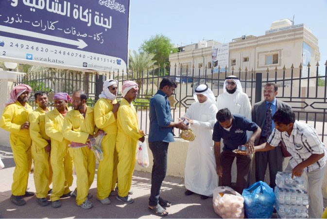 مسؤولو اللجنة يوزعون الوجبات على العمال ﻿