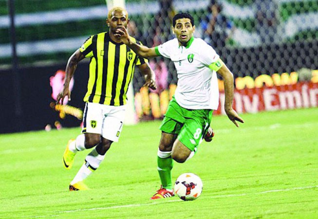 لاعب الاهلي تيسير الجاسم يتقدم بالكرة بملاحقة محترف الاتحاد جوبسون