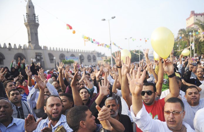 انصار الرئيس المعزول محمد مرسي يرفعون ايديهم بشارة رابعةبعد صلاة العيد امام مسجد عمرو بن العاص امس رويترز