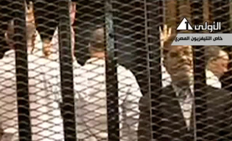 بالفيديو و الصور.. اللقطات الاولى لمحمد مرسي خلف القضبان رافعاً اشارة رابعة 