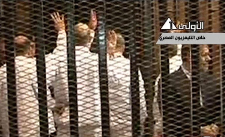 بالفيديو و الصور.. اللقطات الاولى لمحمد مرسي خلف القضبان رافعاً اشارة رابعة 