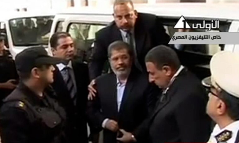 بالفيديو و الصور.. اللقطات الاولى لمحمد مرسي خلف القضبان رافعاً اشارة رابعة 