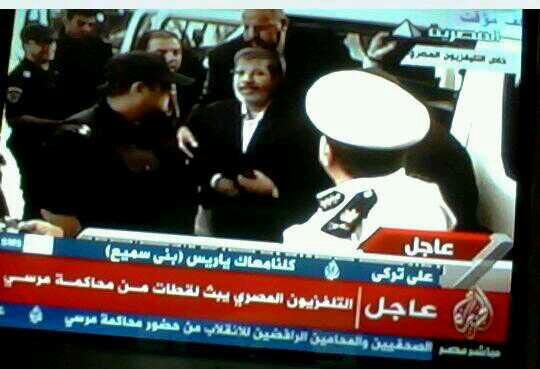 بالفيديو و الصور.. اللقطات الاولى لمحمد مرسي خلف القضبان رافعاً اشارة رابعة 