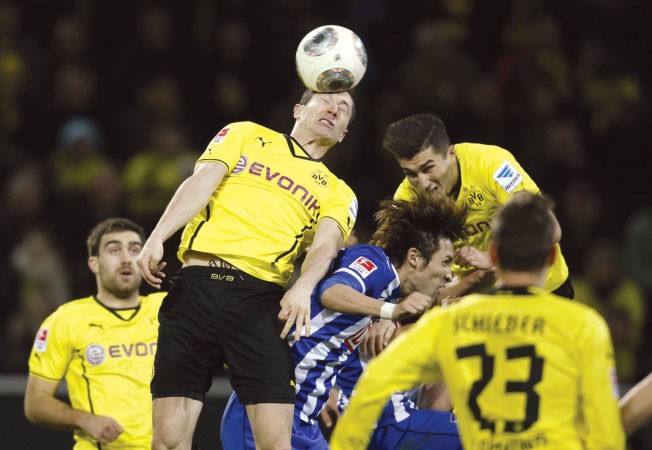لاعب بوروسيا دورتموند روبرت ليفاندوفسكي يحول الكرة براسه وسط مضايقة من مدافعي هرتا برلين	 رويترز﻿