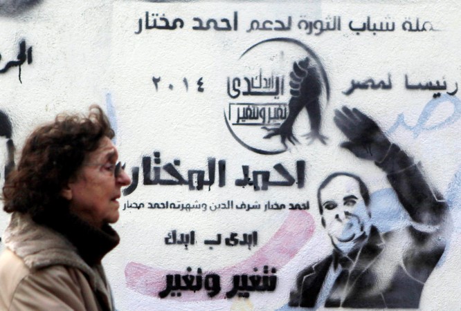 مصرية تمر امام جدار وسط القاهرة عليه شعار حملة دعائية لانتخابات الرئاسة المصرية 2014 رويترز