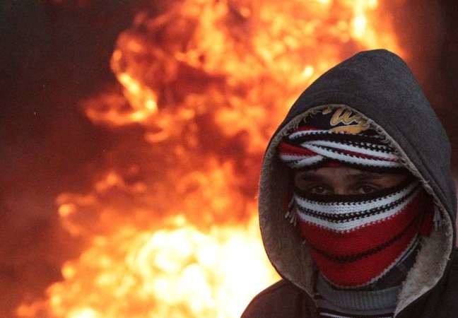 شاب فلسطينيوتبدو النيران خلفه اثر احتجاجات فلسطينيةعلىالتوسع الاستيطاني الاسرائيلي بالضفة امس الاول افب
