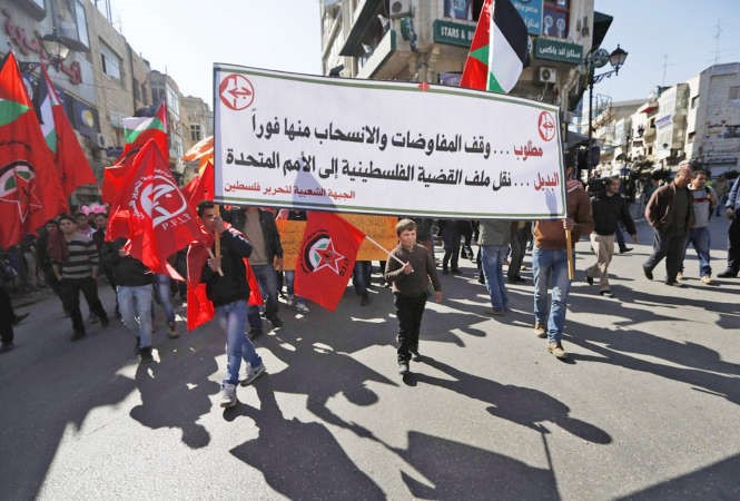  فلسطينيون يرفعون العلم الوطني ولافتات تطالب بالانسحاب من المفاوضات خلال تظاهرة اعتراضا على مقترحات كيري بالضفة امس رويترز 