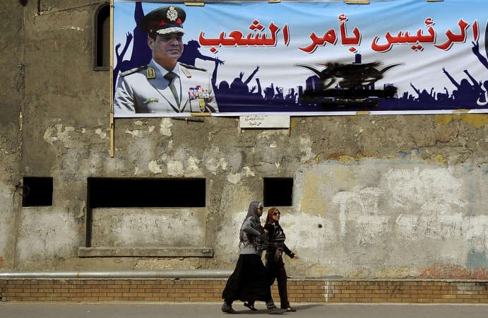 مصريتان تمران تحت لافتة تحمل صورة لوزير الدفاع المصري المشير عبدالفتاح السيسي مكتوبا عليها الرئيس بامر الشعب في الاسكندرية امس 