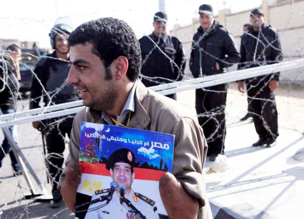 مؤيد لوزير الدفاع المصري المشير عبد الفتاح السيسي يحمل ملصقا له امام شرطة مكافحة الشغب خارج اكاديمية الشرطة امس رويترز