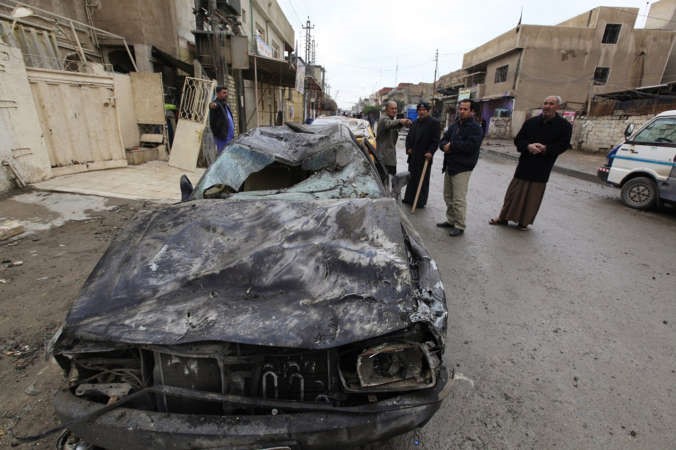  عراقيونيقفون بالقرب من سيارة محطمة اثر تفجير بجنوب بغداد امس		 رويترز ﻿