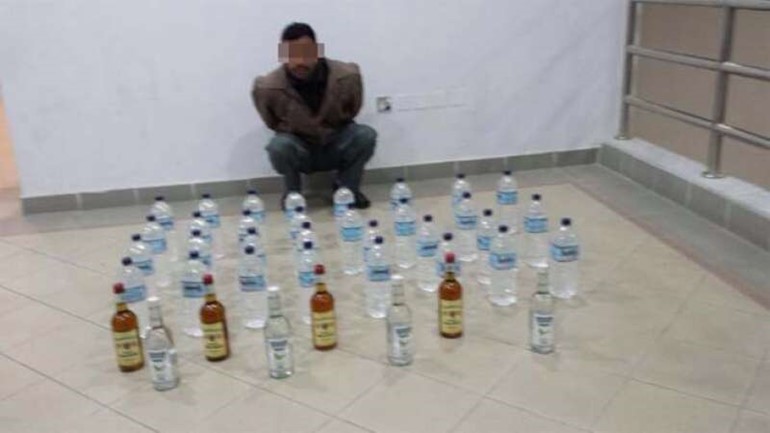 الهندي وامامه كمية الخمور المضبوطة