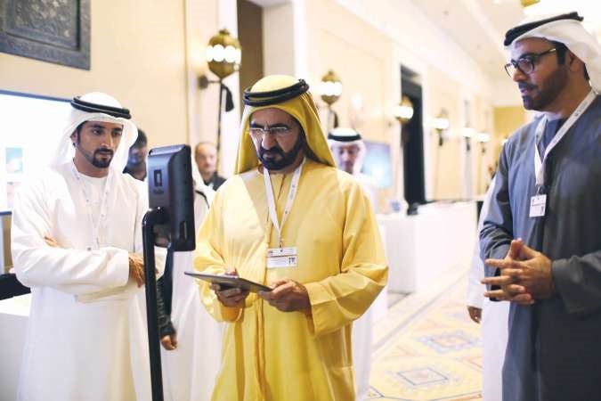  الشيخ محمد بن راشد وهو ينظر الى كمبيوتر لوحي تابلت خلال اختبار الطائرة بدون طيار﻿