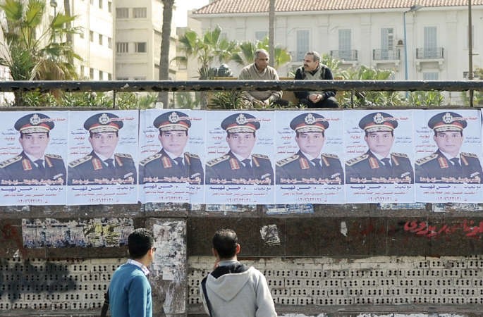 مصريون ينظرون الى صور وزير الدفاع عبدالفتاح السيسي الداعمة لترشحه للرئاسة في الاسكندرية امس الاولافپ