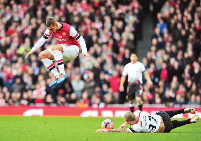 لاعب ارسنال لوكاس بودولسكي يقفز فوق مدافع ليفربولمارتن سكرتل 		 افپ﻿