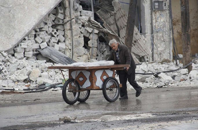 عجوز سوري يدفع عربةفي احد شوارع حلب المدمرةامس افپ
