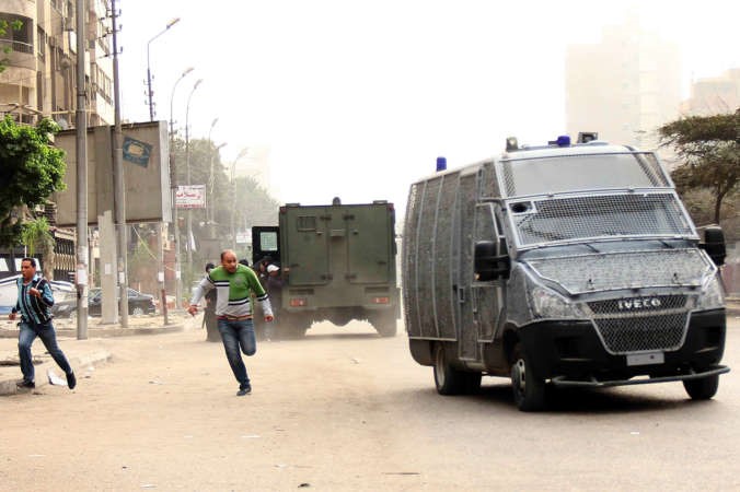  مصريان يهرولان للاحتماء قرب سيارات امن خلال اشتباكات بين متظاهرين والشرطة في القاهرة امس الاول افپ